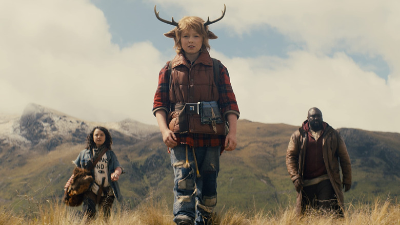 Christian Convery as Gus, walking through a field with Bear and Tommy behind him in Sweet Tooth.