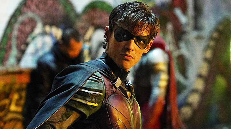 Brenton Thwaites as Robin, looking over his shoulder in an alley in Titans.