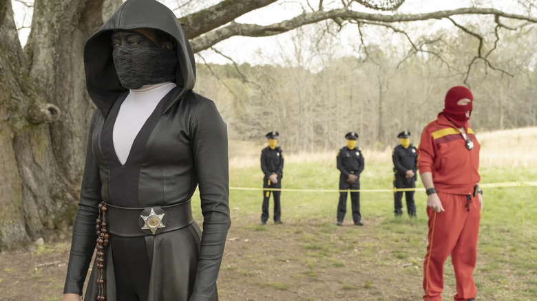 Regina King as Sister Night and Andrew Howard as Red Scare, standing under a tree in Watchmen.