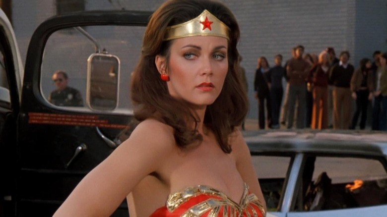 Lynda Carter as Wonder Woman, standing near two cars in Wonder Woman.