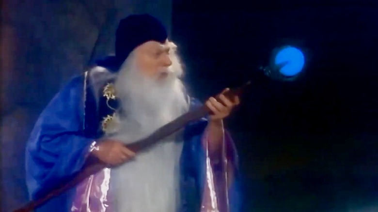 Merlin in blue robe holding staff with blue glowing orb
