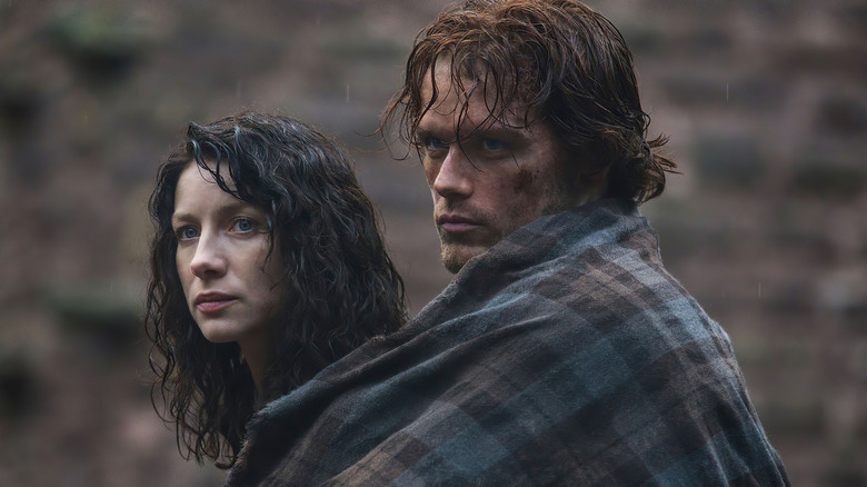Jamie Fraser (Sam Heughan) covers Claire Fraser (Caitríona Balfe) with a flannel blanket in Outlander