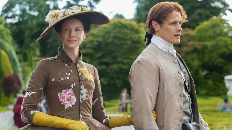 Claire Fraser (Caitríona Balfe) and Jamie Fraser (Sam Heughan) stroll through a French garden in Outlander