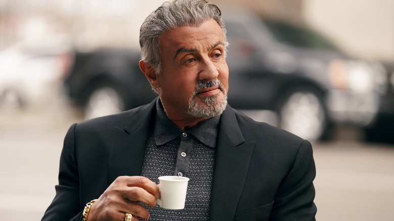 Sylvester Stallone as Dwight "The General" Manfredi holds a small cup on Tulsa King