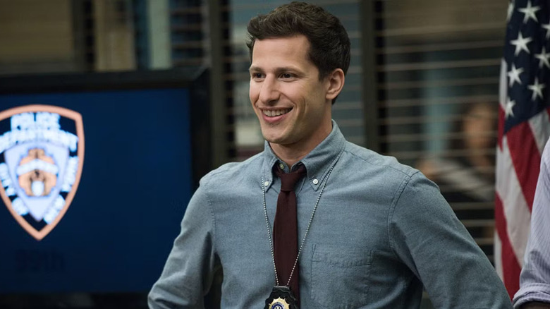Jake (Andy Samberg) smiling in the squad room on Brooklyn Nine-Nine