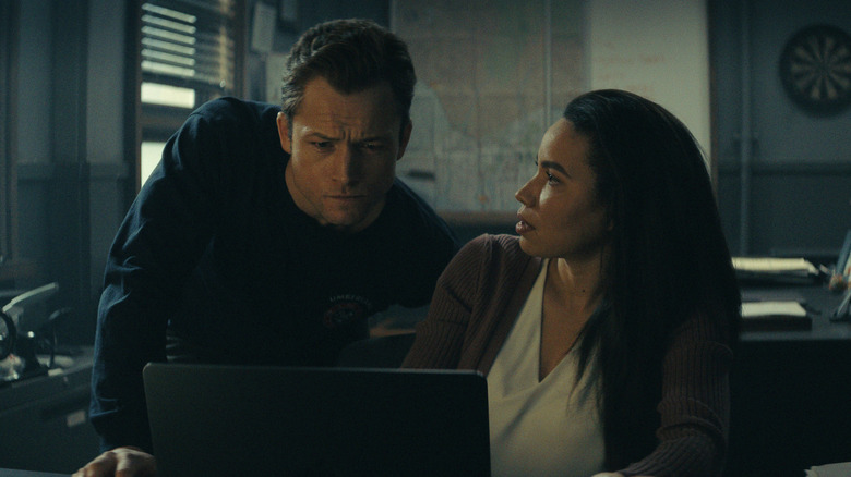 Taron Egerton and Jurnee Smollett as Gudsen and Calderone looking over a laptop in Smoke
