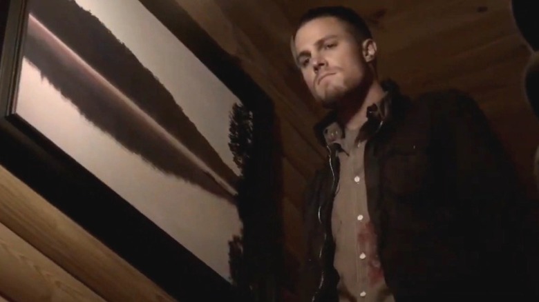 Stephen Amell as Brady in a dimly lit cabin with a serious expression in "The Vampire Diaries."