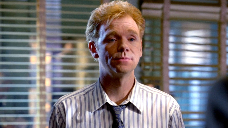 David Caruso beyaz çizgili gömlek ve mavi kravat takıyor 
