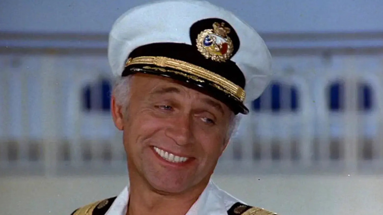 Merrill Stubing (Gavin MacLeod) smiles while wearing his captain uniform in The Love Boat