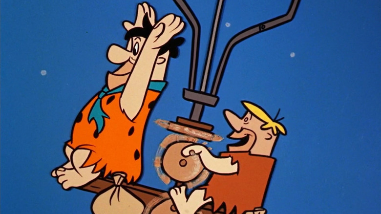 Fred Flintstone and Barney Rubble fly a contraption in the sky in The Flintstones
