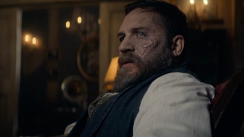 Alfie with his bad eye sat on a sofa in Peaky Blinders