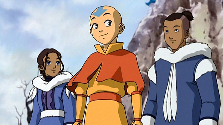 Aang (Zachary Tyler Eisen) stands smiling in front of Katara (Mae Whitman) and Sokka (Jack De Sena) in Avatar: The Last Airbender