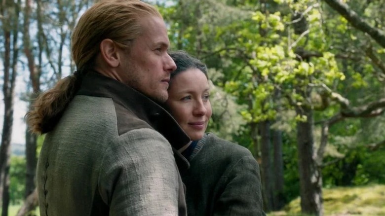 Jamie Fraser (Sam Heughan) and Claire Randall (Caitríona Balfe) embrace in a forest in Outlander
