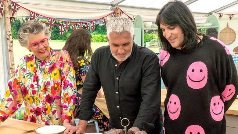 Prue Leith, Paul Hollywood, and Noel Fielding looking down at baked goods in The Great British Baking Show