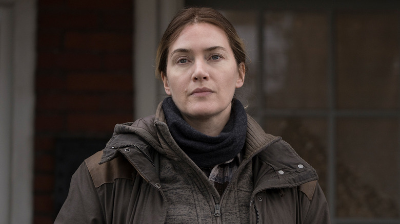 Kate Winslet as Mare Sheehan standing outside in "Mare of Easttown."