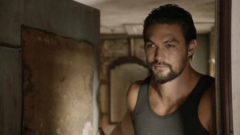 Phillip Kopus (Jason Momoa) stands in the doorway of an abandoned building in The Red Road