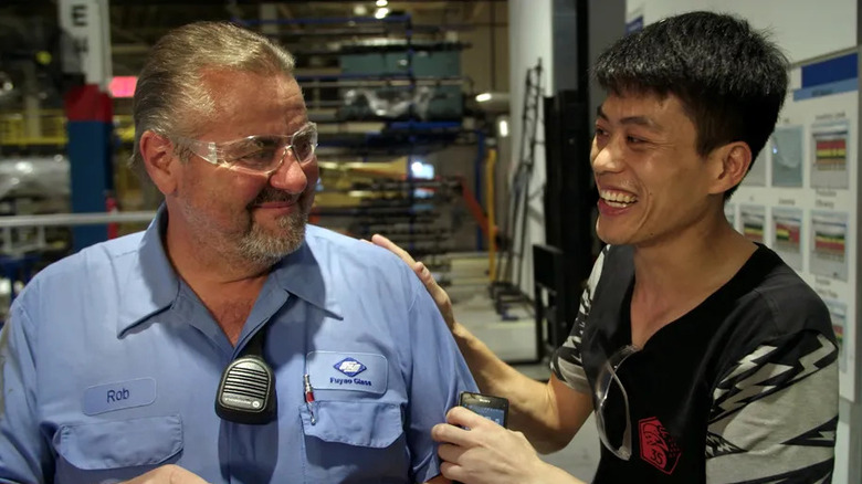 An American and a Chinese factory worker smile together in American Factory.