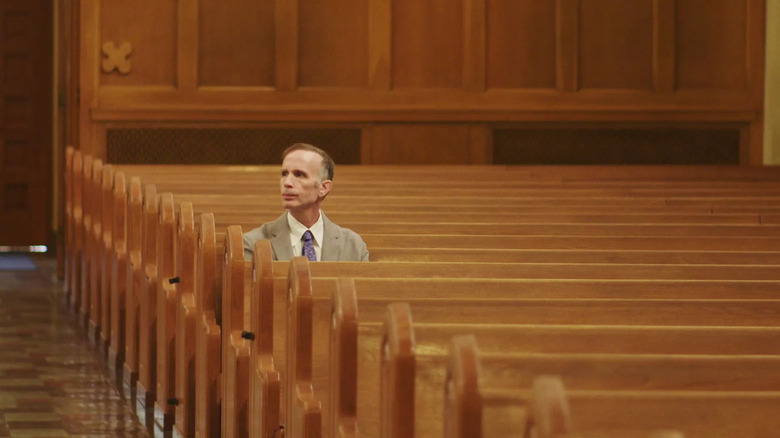 A man sits alone in a church in Procession.
