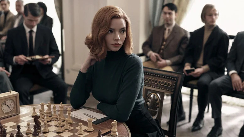 Anya Taylor-Joy as Beth Harmon sitting in front of chess table at tournament in The Queen's Gambit
