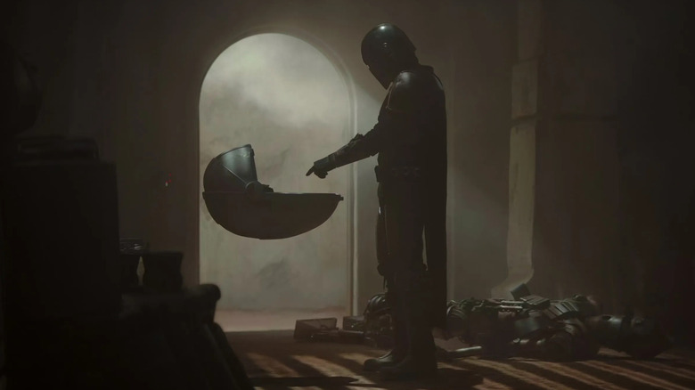 Din Djarin holding out his finger at a floating cradle in The Mandalorian