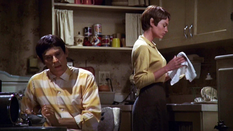 T'Pol (Jolene Blalock) washes dishes while Mestral (J. Paul Boehmer) sits at a table in Star Trek: Enterprise