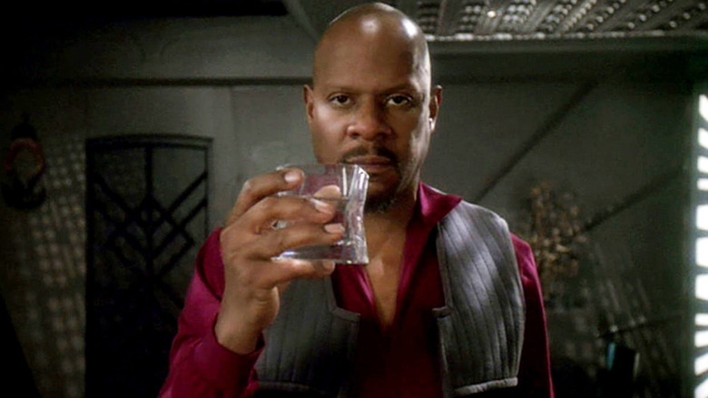 Benjamin Sisko (Avery Brooks) solemnly holds up a glass of whiskey in Star Trek: Deep Space Nine