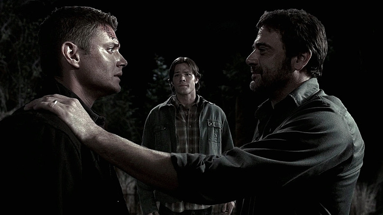John Winchester (Jeffrey Dean Morgan) smiles and puts a hand on the shoulder of Dean Winchester (Jensen Ackles) while Sam Winchester (Jared Padalecki) watches in Supernatural