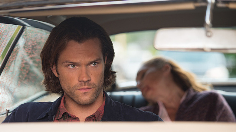 Sam Winchester (Jared Padalecki) sits in a car with a dead woman in the backseat in Supernatural