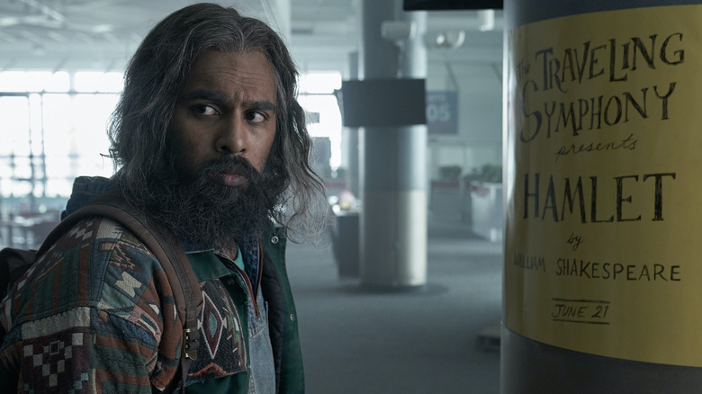 Jeevan Chaudhary looking over his shoulder next to an ad for a Hamlet production