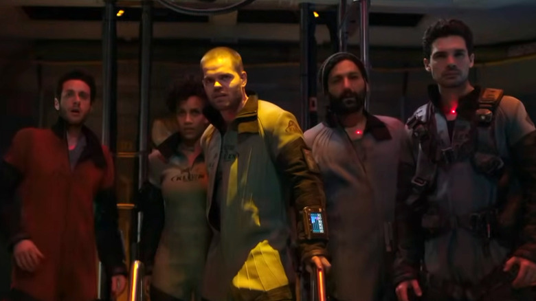 Five people brace themselves on a spaceship.