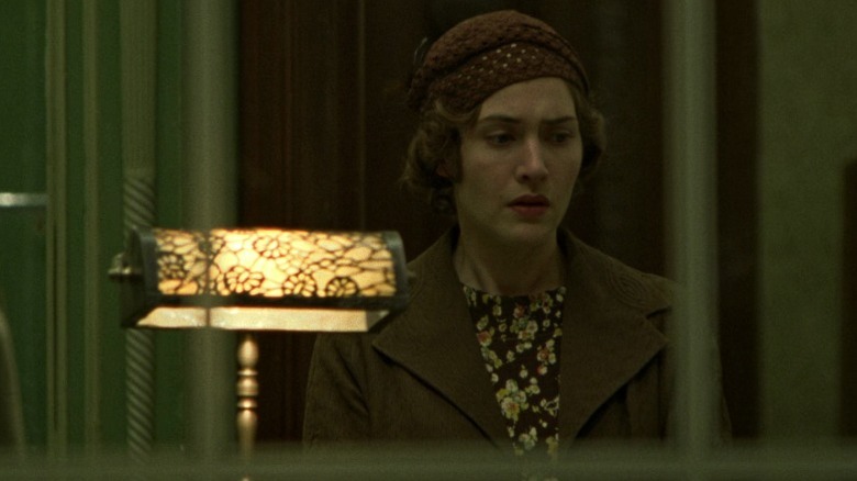 Mildred Pierce standing behind a glass pane and looking down on Mildred Pierce S1E1