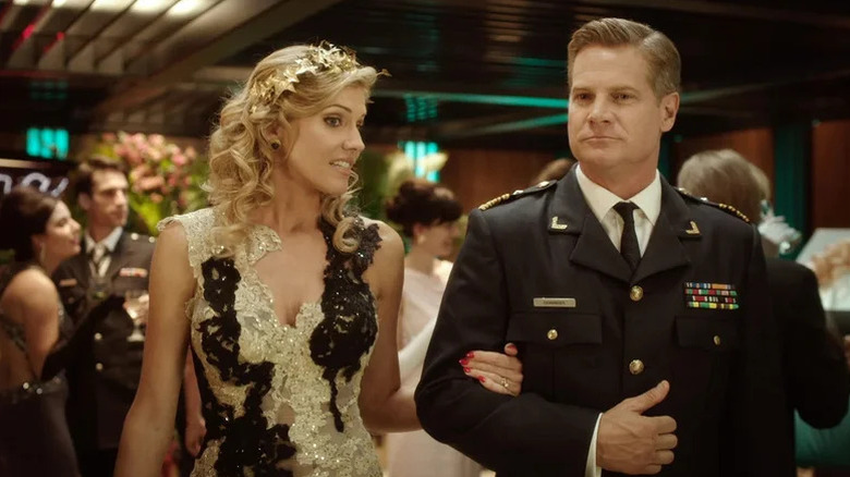 Tricia Helfer in black and white dress walking next to Brian Van Holt as Captain Denninger in military suit in Ascension