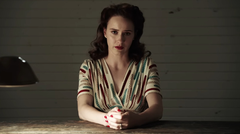 Rachel Brosnahan sitting at table with arms crossed in Manhattan