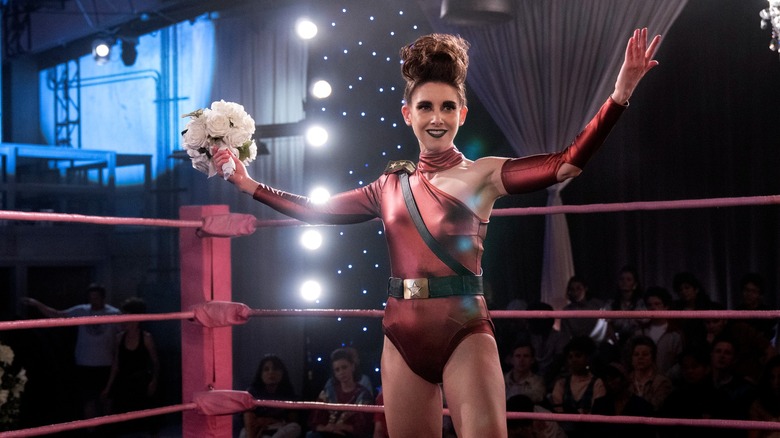Ruth (aka Zoya the Destroya) inside the ring, arms out, smiling and holding flowers