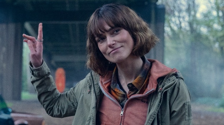 Helen Webb standing outside with her head tilted to the right and her right arm up in Black Doves