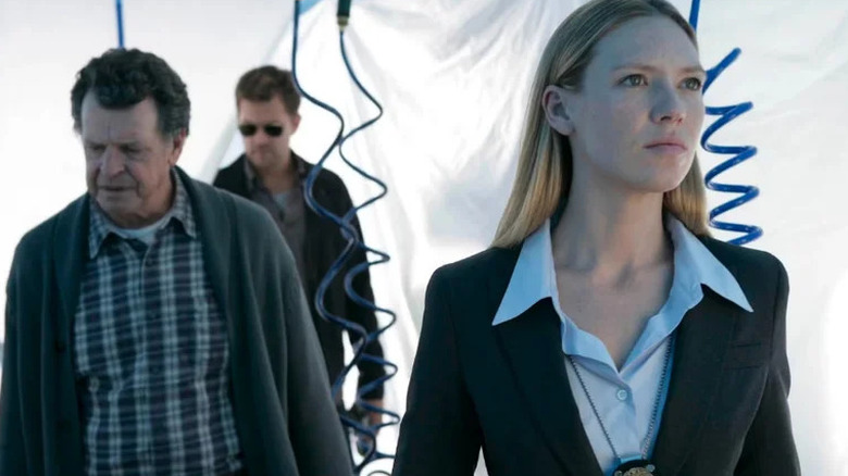 Anna Torv as Olivia standing in front of white plastic with John Noble as Walter and Joshua Jackson as Peter in Fringe