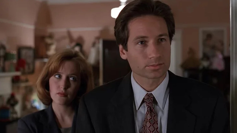 Gillian Anderson as Dana Scully standing behind David Duchovny as Fox Mulder in The X-Files