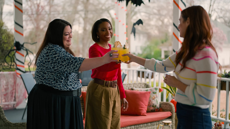 Dana Sue Sullivan (Brooke Elliott), Helen Decatur (Heather Headley), and Maddie Townsend (JoAnna Garcia Swisher) toast each other on a front porch in Sweet Magnolias