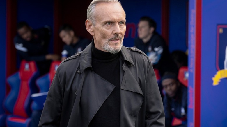 Anthony Head as Rupert Mannion, walking near AFC Richmond's bench in Ted Lasso.