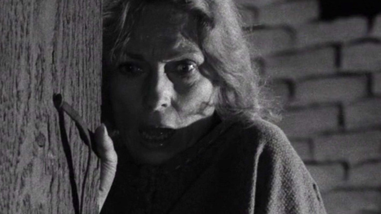 A terrified woman (Agnes Moorehead) clutches a wooden door in The Twilight Zone (1959)