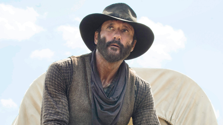 James Dutton (Tim McGraw) wearing a hat and looking up in 1883