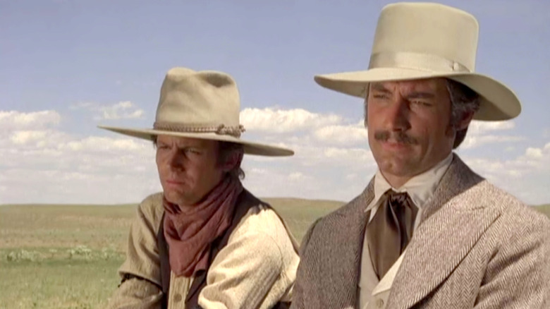 A discerning Oliver Seccombe (Timothy Dalton) sits with one of his associates in Centennial