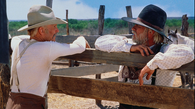 Woodrow Call (Tommy Lee Jones) glances at Gus McCrae (Robert Duvall) while leaning on a fence in Lonesome Dove