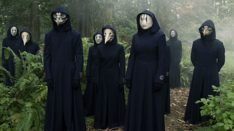 A group of hooded and masked figures in the forest on The Order