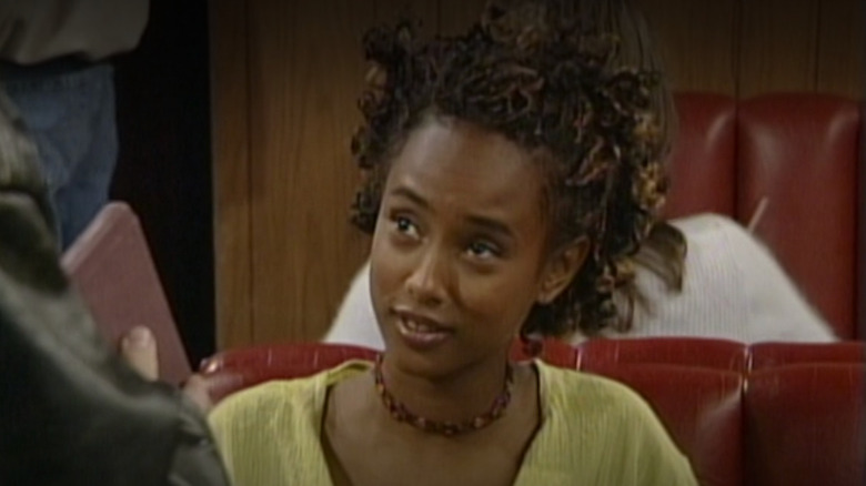 Trina McGee-Davis as Angela Moore sitting in a booth and smiling in Season 5 of Boy Meets World