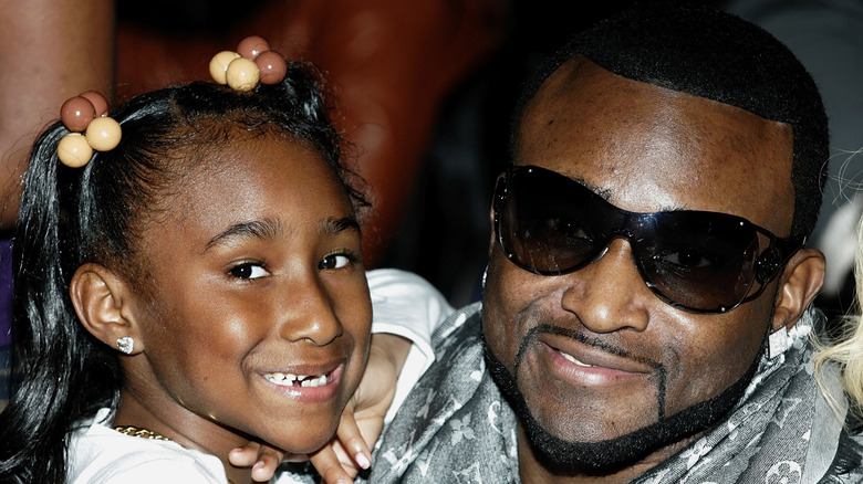 Shawty Lo with sunglasses holding his daughter
