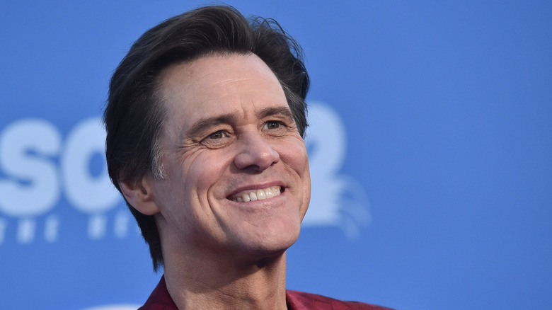 Jim Carrey smiling and wearing a red jacket
