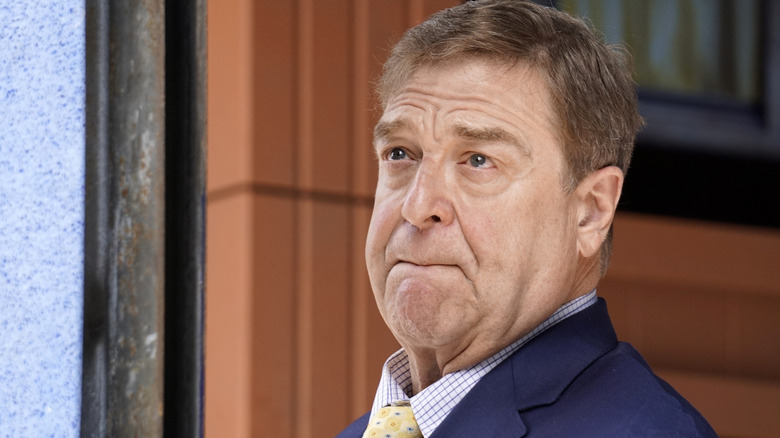 John Goodman looking serious and wearing a yellow tie