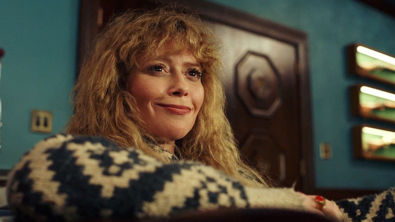 Charlie Cale (Natasha Lyonne) sits smiling smugly in Poker Face