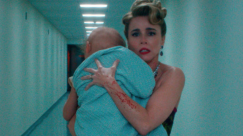 Pamela Voorhees holding a baby wrapped in a blue blanket with a blood stains on her arm